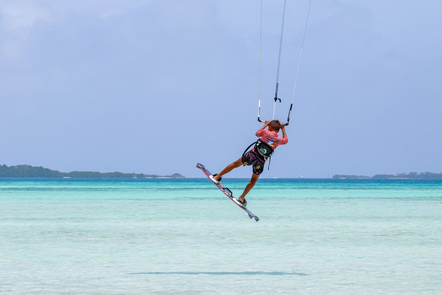 A kitesurfer boosting above the shallow lagoon